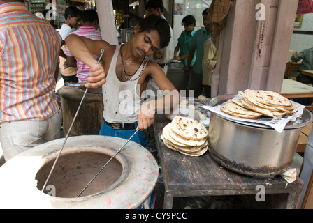 A street vendor removes chapatis from a tandoor (clay oven) in Old Delhi, India Stock Photo