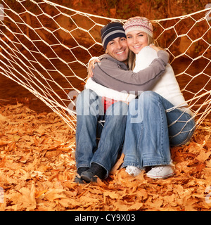 Picture of happy young family hugging in autumnal park, cheerful smiling couple swinging in hammock on backyard Stock Photo