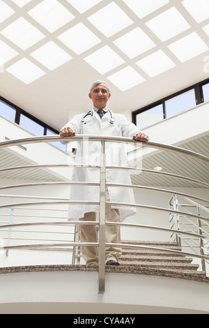 Doctor standing an the railing at the corridor looking down Stock Photo