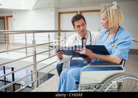Doctor and nurse in wheelchair studying folder Stock Photo