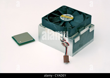A PC central processor unit (CPU) chip and its heat sink with cooling fan standing on a plain background Stock Photo