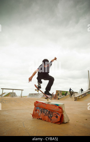 Skateboarder jumping alone over an obstacle in Parque Tejo, Lisbon, Portugal Stock Photo