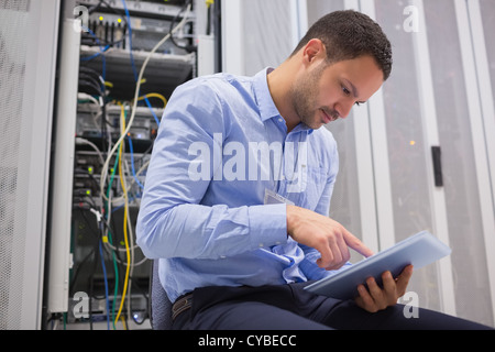Man using tablet pc beside servers Stock Photo