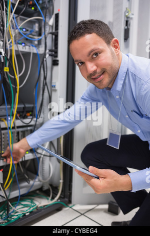 Technician plugging in cables and using tablet pc Stock Photo