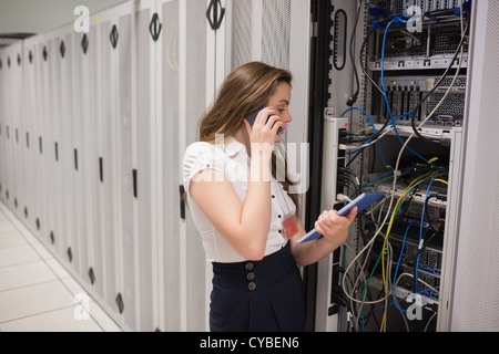 Woman on the phone holding tablet pc checking the servers Stock Photo