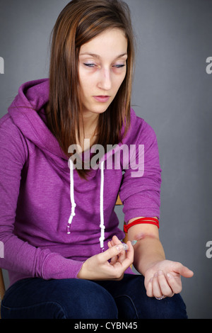 Young woman injecting drugs, like heroin, and getting high Stock Photo
