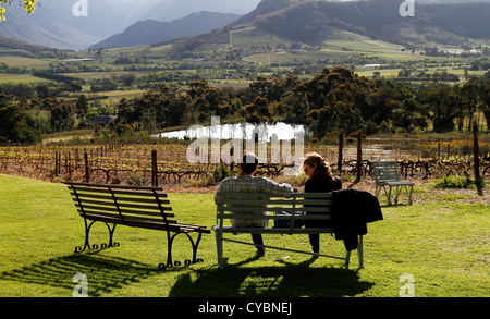 A couple enjoy late afternoon sun and view over the valleyon the lawns of La Petite Ferme restaurant, Franschhoek, South Africa. Stock Photo