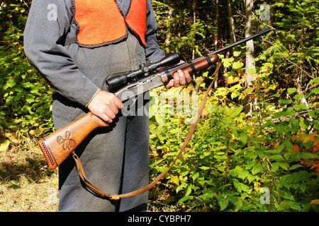 Man hunter with riffle in his hands, autumn forest behind Stock Photo