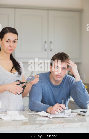 Woman cutting up credit card with man calculating finances Stock Photo