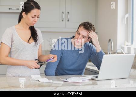 Wife cutting up credit card with husband watching Stock Photo