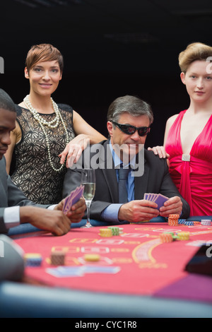 Man in sunglasses smiling at poker table Stock Photo