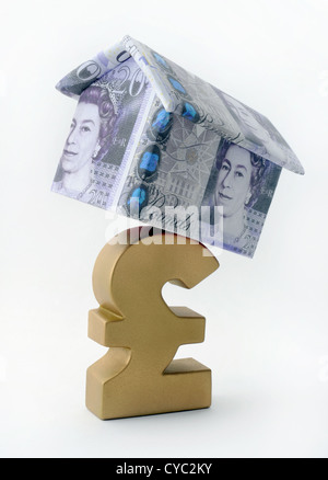 HOUSE MADE OF BRITISH CURRENCY BALANCING ON POUND SIGN RE SAVINGS MORTGAGES INCOMES WAGES THE ECONOMY RECESSION FIRST BUYERS UK Stock Photo