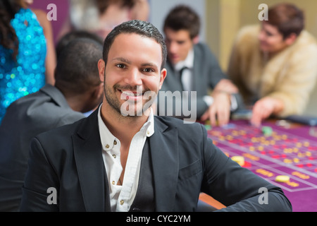 Smiling man sitting leaning on roulette table Stock Photo