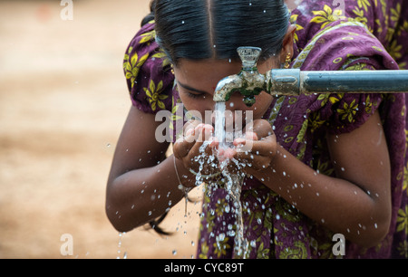 Indian girl drinking from a communal water tap in rural indian village. Andhra Pradesh, India Stock Photo