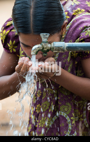 Indian girl drinking from a communal water tap in rural indian village. Andhra Pradesh, India Stock Photo