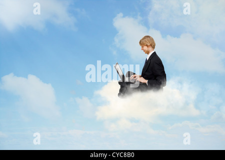 Young business man sitting on clouds and using a laptop Stock Photo