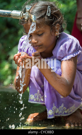 Indian girl drinking from a communal water tap in rural indian village. Andhra Pradesh, India Stock Photo