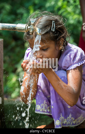 Indian girl drinking from a communal water tap in rural indian village. Andhra Pradesh, India Stock Photo