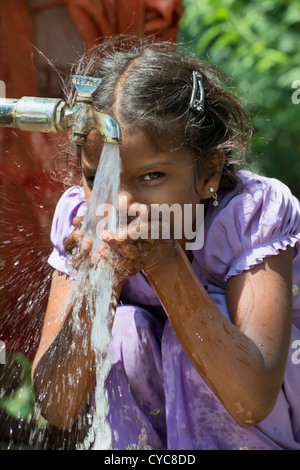 Indian girl drinking from a communal water tap in rural indian village. Andhra Pradesh, India Stock Photo