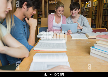 Students in the library studying with two using tablet pc Stock Photo