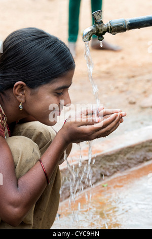 Indian girl drinking from a communal water tap in rural indian village. Andhra Pradesh, India Stock Photo