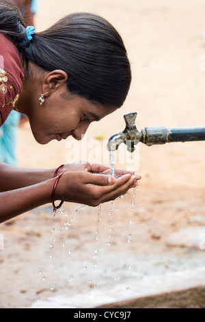 Indian girl drinking from a communal water tap in rural indian village. Andhra Pradesh, India Stock Photo