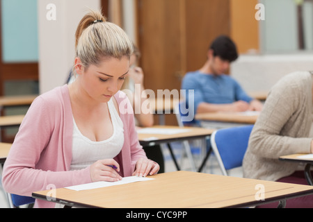 Woman writing note in classroom Stock Photo