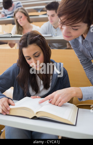 Lecturer pointing to something on student's book Stock Photo