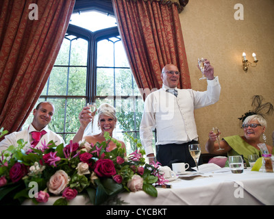 The Father of the Bride toasts the bride and groom on their wedding day, with a beaming mother of the bride looking on Stock Photo