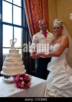 A bride and groom cut the cake on their wedding day Stock Photo