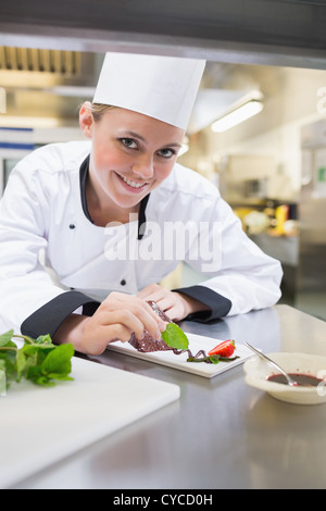 Smiling chef putting mint on the plate Stock Photo