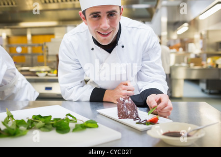 Smiling chef putting mint with his dessert Stock Photo