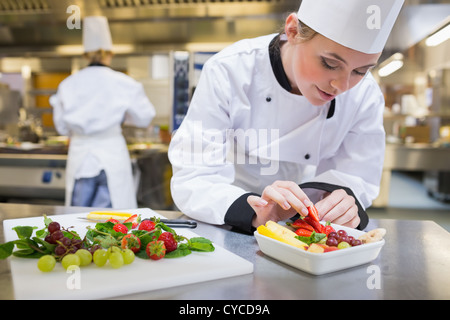 Chef putting a strawberry in the fruit salad Stock Photo