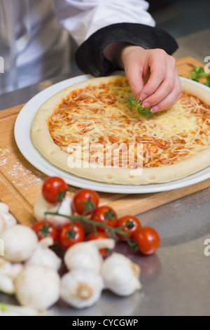 Pizza being garnished with basil leaf Stock Photo