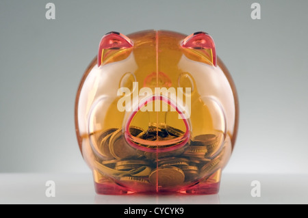 orange translucent piggy bank and coins Stock Photo