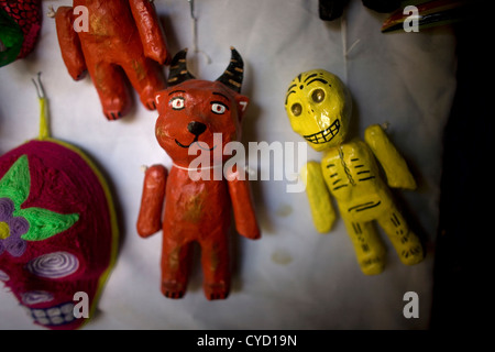Paper mache dolls representing a red devil and a yellow skeleton sit for sale in a Mexican folk-art workshop in Mexico City Stock Photo