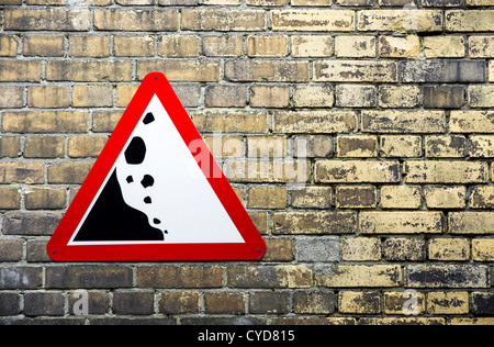 Yellow brick wall with triangle warning sign on left side Stock Photo