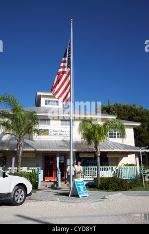 raising the american flag on a flagpole outside the chamber of commerce building in key largo florida keys usa Stock Photo