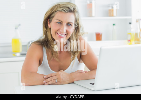 Woman sitting in the kitchen and using laptop Stock Photo