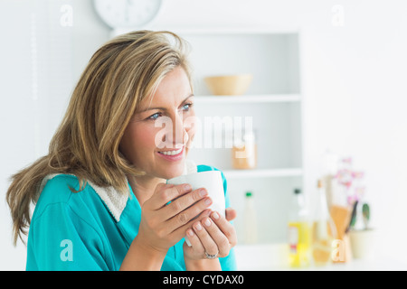 Smiling woman holding mug and wearing bathrobe Stock Photo