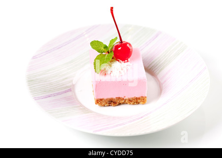 Pink cheesecake with maraschino cherry and mint on plate Stock Photo