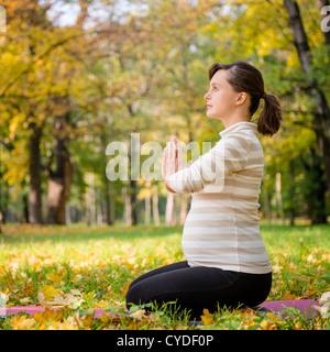 Young pregnant woman meditating outside in beautiful autumn nature Stock Photo