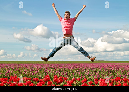Young enthousiastic guy jumping up from the tulip fields in the Netherlands Stock Photo