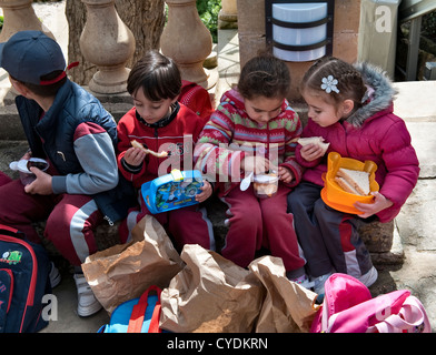 Small children eating their packed lunches while on a school trip to the President's Kitchen Garden, Attard, Malta Stock Photo