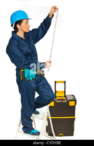Builder woman standing on stepladder and making measurements isolated on white background Stock Photo
