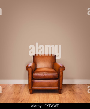 Leather armchair on a wooden floor against a plain background wall with lots of copyspace. The wall has a clipping path.