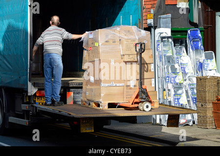 Moving boxes off of lorry making a supplier merchandise delivery outside a High Street shop lowering to pavement using tailgate lift Sevenoaks Kent UK Stock Photo