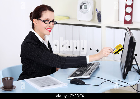 Businesswoman holding credit card in front of the computer. Stock Photo