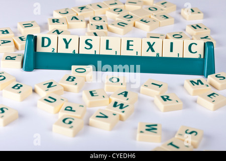 'Dyslexic' spelled out using scrabble letter tiles in amongst assorted scrabble letter tiles emphasizing how letters get jumbled Stock Photo