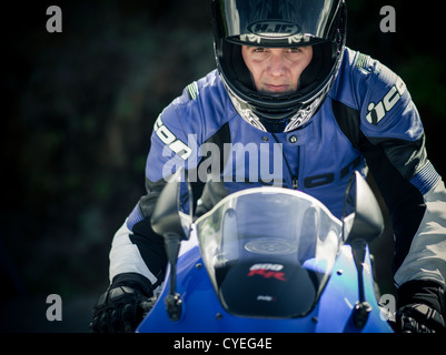 Man on motorbike in full safety protection gear. Helmet, leather jacket, gloves on a Honda CBR600RR sport bike. Stock Photo